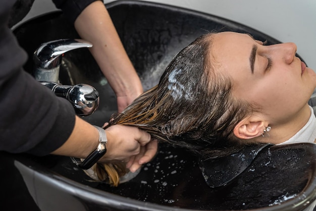 Vista dall'alto come un maestro colorista lava i capelli della testa di una giovane ragazza in un salone di bellezza