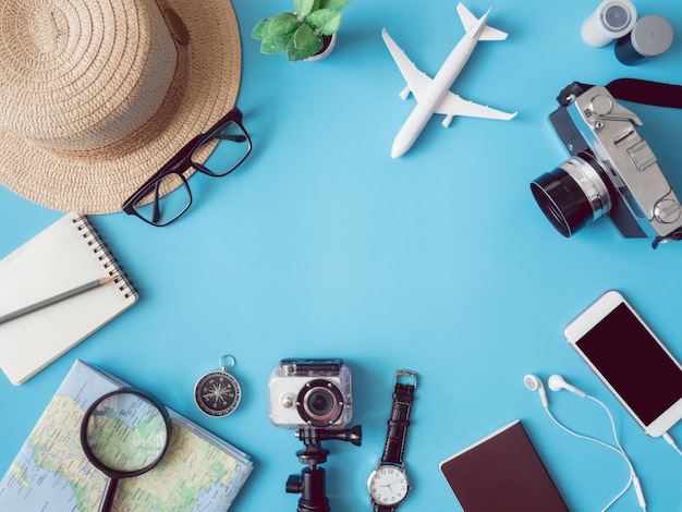 Vista dall'alto concetto di viaggio con pellicole per fotocamere retrò, mappa, passaporto, smartphone, action camera e bussola su sfondo blu con spazio di copia, elementi essenziali turistici, effetto tono vintage