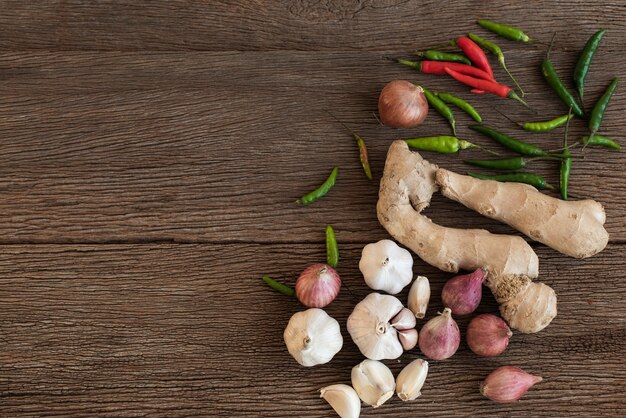 Vista dall'alto degli ingredienti da cucina sono cipolla, peperoncino, zenzero e aglio su uno sfondo di legno. Spezie della Thailandia