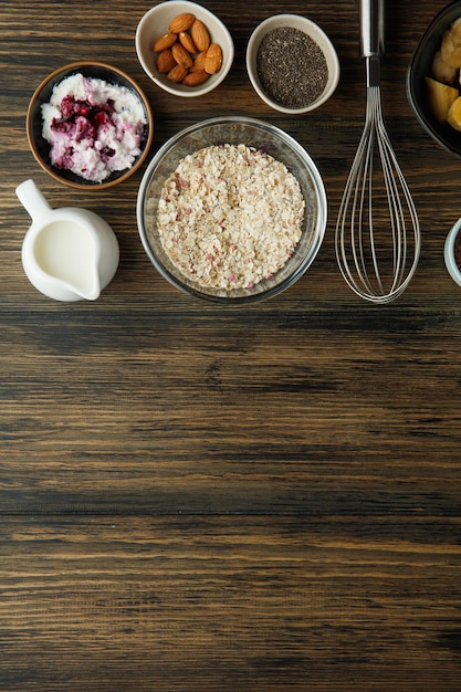 Vista dall'alto degli ingredienti per la colazione come ricotta di banana e avena latte di mandorla con frusta su fondo di legno con spazio per la copia