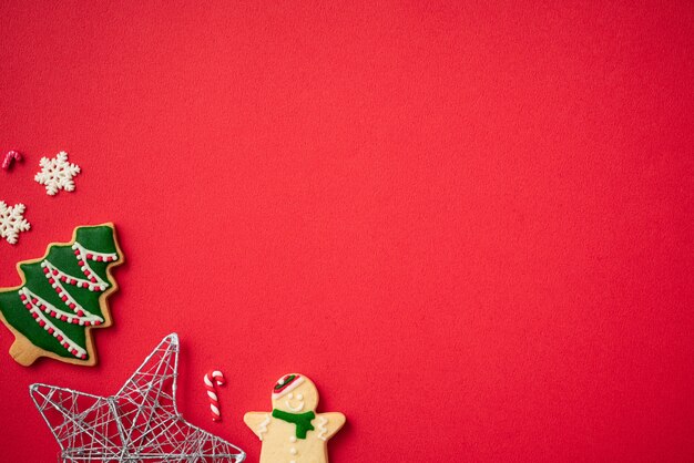 Vista dall'alto dei biscotti di panpepato di Natale decorati con decorazioni su sfondo rosso della tavola con spazio per le copie, concetto di celebrazione delle vacanze.