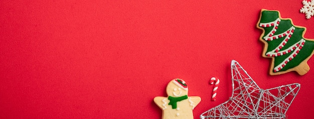 Vista dall'alto dei biscotti di panpepato di Natale decorati con decorazioni su sfondo rosso della tavola con spazio per le copie, concetto di celebrazione delle vacanze.