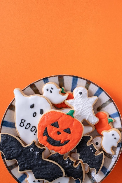 Vista dall'alto dei biscotti di zucchero a velo decorati festivi di Halloween su sfondo arancione