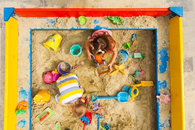 Vista dall'alto dei giochi per bambini nella sandbox. Ragazzo e ragazza giocano al parco giochi. Concetto di creazioni, giocattoli coloufrul