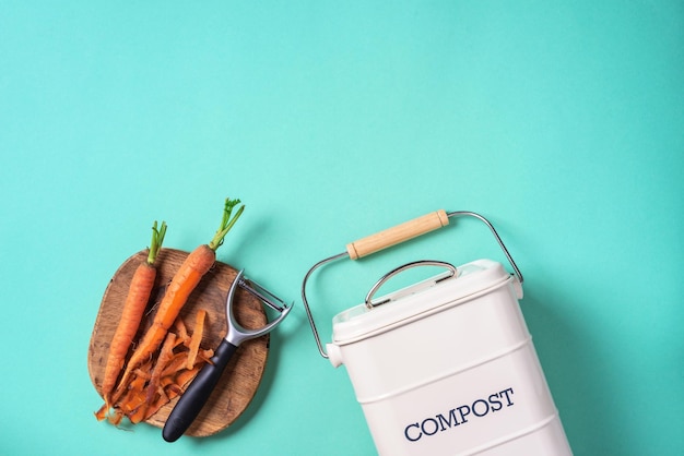 Vista dall'alto dei rifiuti alimentari della cucina raccolti nel vaso di compostaggio per il riciclaggio Verdure sbucciate sul tagliere bidone di compostaggio bianco su sfondo blu