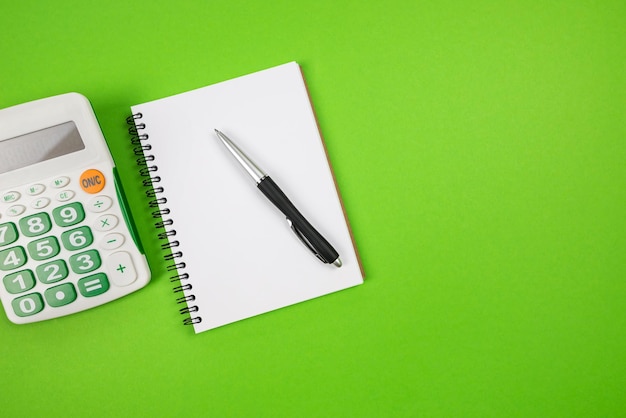 Vista dall'alto del blocco note con penna e calcolatrice su sfondo verde copia spazio