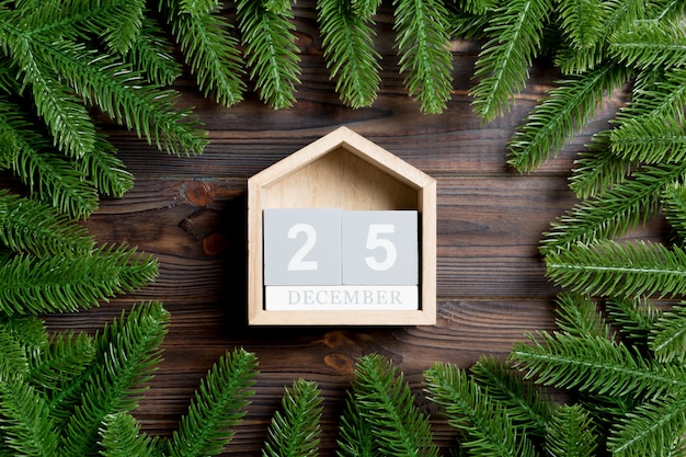 Vista dall'alto del calendario decorato con una cornice fatta di abete sul tavolo di legno. Il venticinque dicembre. Concetto di tempo di Natale