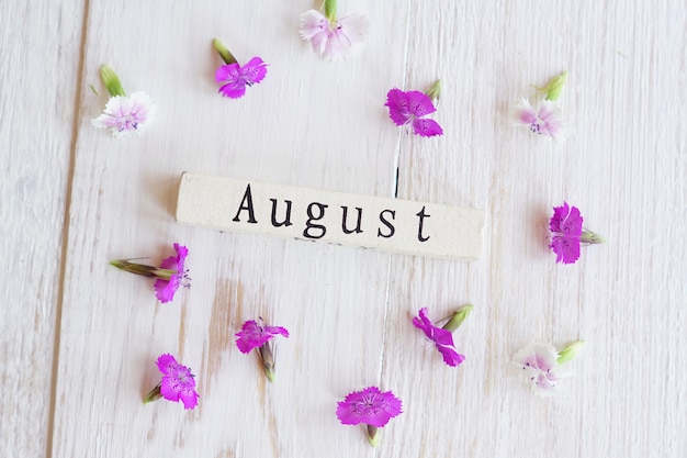 Vista dall&#39;alto del calendario in legno con sighn di luglio e fiori rosa.