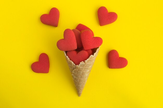 Vista dall'alto del cono gelato con biscotti a forma di cuore rosso sul giallo