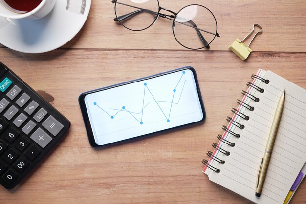 Vista dall'alto del display del grafico azionario sullo smartphone sul tavolo