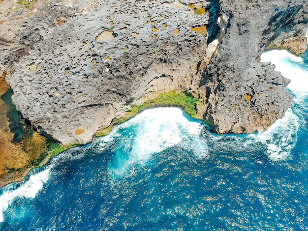 Vista dall'alto del drone aereo della spiaggia di corallo e delle onde dell'oceano blu a Nusa Penida Bali Indonesia Vista aerea della costa rocciosa e delle insenature