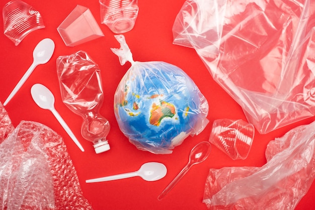 Vista dall'alto del globo in sacchetto di plastica con immondizia intorno isolato sul concetto di riscaldamento globale rosso