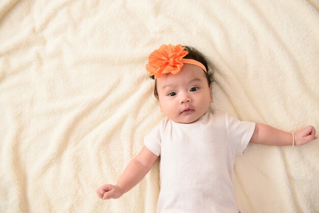 Vista dall'alto del grazioso piccolo bambino asiatico che indossa la fascia di fiori d'arancio