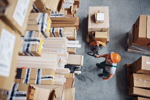 Vista dall'alto del lavoratore di sesso maschile in magazzino con transpallet.