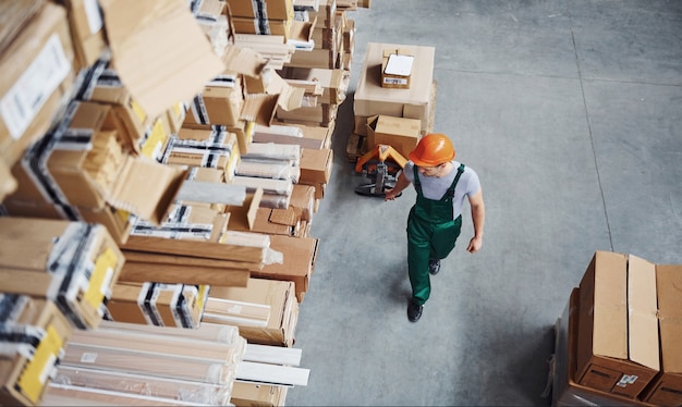 Vista dall'alto del lavoratore di sesso maschile in magazzino con transpallet.