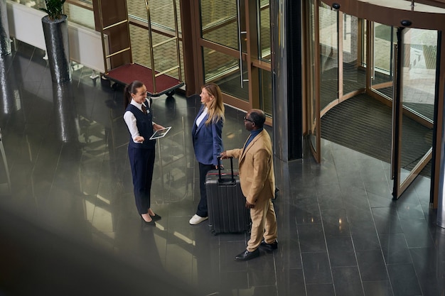 Vista dall'alto del manager con tablet digitale che incontra gli ospiti dell'hotel