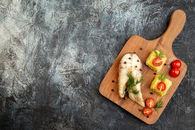 Vista dall'alto del pasto di grano saraceno di pesce bollito servito con formaggio verde di pomodori sul tagliere di legno sulla superficie del ghiaccio