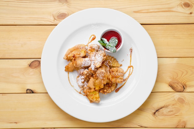 Vista dall'alto del piatto con frutta fritta nel grasso bollente impanata con caramello e marmellata di fragole