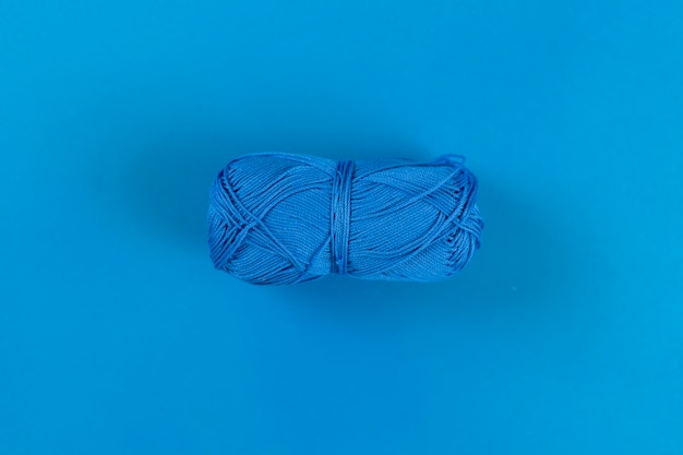 Vista dall'alto del singolo rotolo di filo isolato per lavorare a maglia l'artigianato fatto in casa sulla superficie colorata
