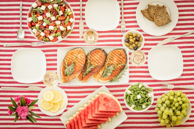 Vista dall'alto del tavolo con pesce, insalate, frutta e verdura