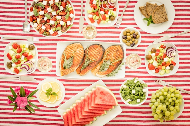 Vista dall'alto del tavolo con pesce, insalate, frutta e verdura