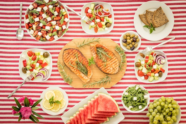 Vista dall'alto del tavolo con pesce, insalate, frutta e verdura