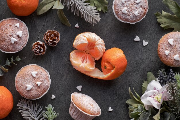 Vista dall'alto del tavolo con satsuma, muffin zuccherati e biscotti con stelle di Natale su oscurità