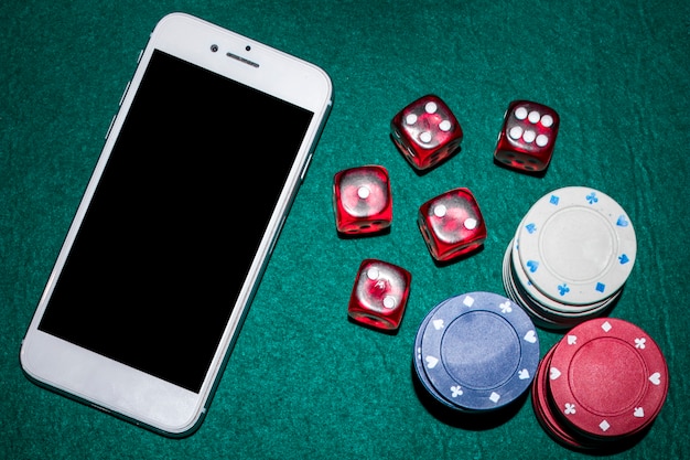 Vista dall&#39;alto del tavolo da poker con dadi rossi; chip e smartphone del casinò