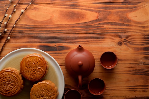 Vista dall'alto del tavolo rustico con tradizionali torte della luna, servizio da tè e spazio di copia. Il carattere cinese sulla torta della luna rappresenta "cinque noccioli e maiale arrosto" in inglese