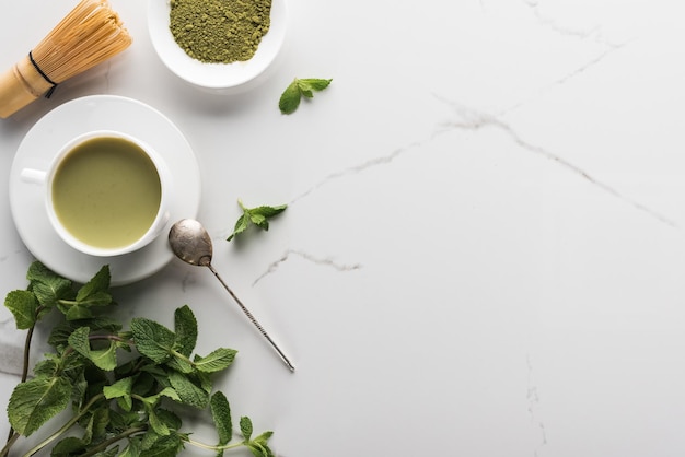 Vista dall'alto del tè verde matcha con menta sul tavolo bianco