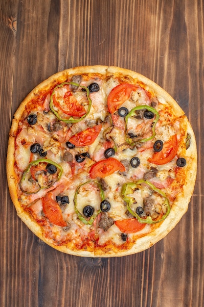 Vista dall'alto deliziosa pizza al formaggio su una superficie di legno marrone