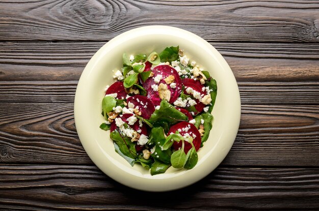 Vista dall'alto dell'insalata mediterranea di barbabietole arrosto con feta di noci e foglie di purè sul tavolo di legno