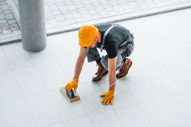 Vista dall'alto dell'uomo in uniforme grigia che installa la piastra all'interno di un grande ufficio moderno durante il giorno