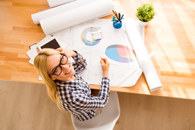 Vista dall'alto della bella ragazza con gli occhiali che lavora con i diagrammi