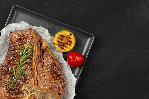 Vista dall'alto della bistecca alla fiorentina alla griglia con spezie sulla tavola nera