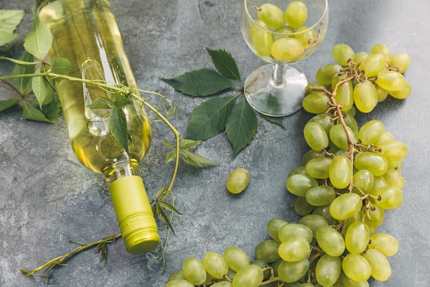 Vista dall'alto della bottiglia di vino bianco bicchiere di vino verde e uva matura su sfondo vintage tavolo in pietra grigia...