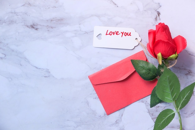 Vista dall'alto della busta del contenitore di regalo e del fiore di rosa su fondo bianco