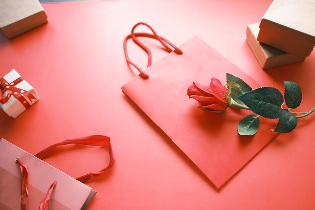 Vista dall'alto della confezione regalo e del fiore di rosa su sfondo rosso