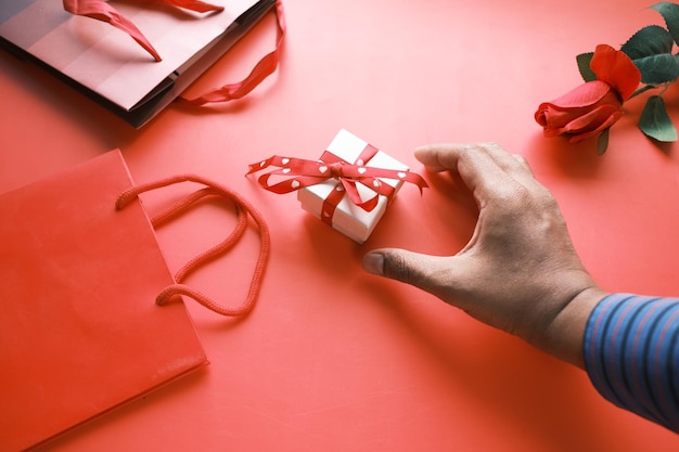 Vista dall'alto della confezione regalo e del fiore di rosa su sfondo rosso