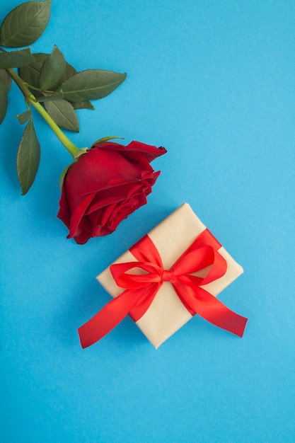 Vista dall'alto della confezione regalo e rosa rossa su sfondo blu