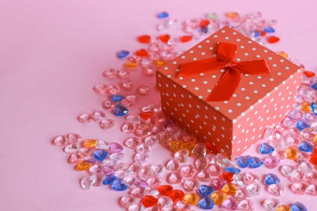 Vista dall'alto della confezione regalo rossa con marmi a forma di cuore su sfondo rosa