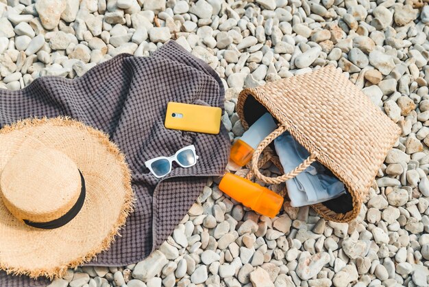 Vista dall'alto della coperta da spiaggia con cappello di paglia crema per la protezione solare con borsa piatta