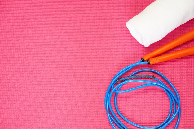 Vista dall'alto della corda per saltare e dell'asciugamano sul tappetino Yoga rosso Concetto di fitness e sano con spazio per la copia