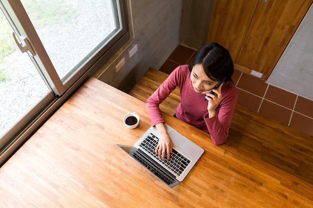 Vista dall'alto della donna parla al cellulare e usa il computer portatile