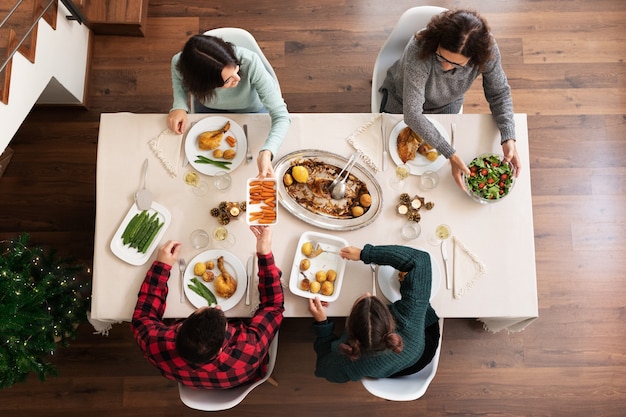 Vista dall'alto della famiglia che cena insieme di Natale Passando i piatti lungo Servire il cibo Vacanze