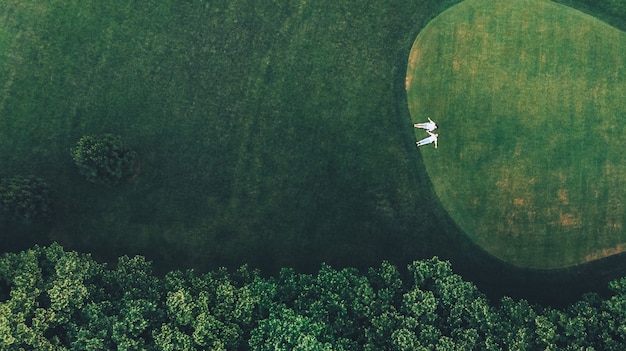 Vista dall'alto della giovane coppia si trova mano nella mano sul campo da golf