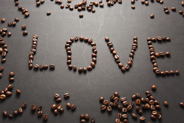 Vista dall'alto della lettera amore, parola composta da chicchi di caffè su sfondo nero per il design