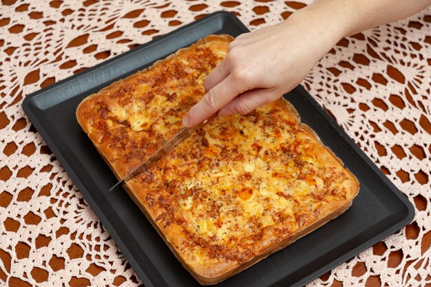 Vista dall'alto della mano della donna che taglia la torta salata del frullatore brasiliano Cibo tradizionale brasiliano