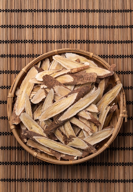 Vista dall'alto della radice di astragalo della medicina tradizionale cinese a base di erbe sul fondo della tavola in legno.