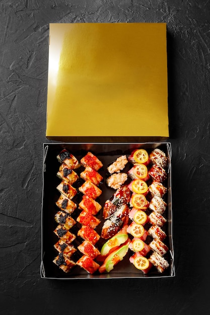 Vista dall'alto della scatola di cartone con uramaki nigiri sushi e gunkan maki con tonno salmone e anguilla